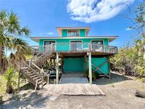 Charming two-story beach house with a wooden deck and staircase, perfect for enjoying coastal living at 9580 Almirate Ct, Placida, FL 33946