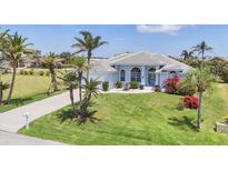 Beautiful one-story home with well-manicured lawn, lush landscaping, and a light blue exterior paint at 11 Amberjack Ln, Placida, FL 33946
