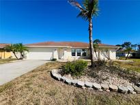 Inviting single-story home featuring a two-car garage, concrete driveway, and lush landscaping at 1155 Osceola Blvd, Englewood, FL 34223