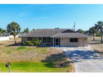 Charming single-story home with a well-maintained lawn, complemented by palm trees and a long driveway at 11869 Newgate Ave, Port Charlotte, FL 33981