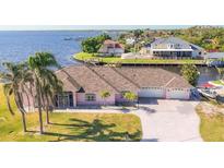 Sprawling waterfront home with mature palm trees, a long driveway, and an attached two car garage at 12445 Krome Ave, Port Charlotte, FL 33981