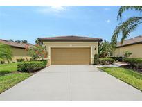 Attached two-car garage in well-manicured front yard with shrubbery and trees at 1318 Ballota Ln, North Port, FL 34289