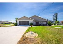 Well-maintained, single-story home with an attached garage, lush green lawn, and inviting curb appeal under a clear blue sky at 204 Bunker Rd, Rotonda West, FL 33947