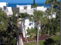 Tropical white condo building, B3 unit, surrounded by palms, fronted by walkway, with ocean view at 2950 N Beach Rd # B324, Englewood, FL 34223