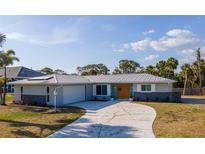 Charming single-story home featuring a well-manicured lawn, and a stone accent wall and a driveway that leads to an attached garage at 360 E Wentworth Cir, Englewood, FL 34223