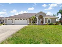 Charming single-story home featuring a well-manicured lawn, three-car garage, and inviting entrance at 39 Medalist Ln, Rotonda West, FL 33947