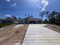 Newly built single-Gathering home with a three-car garage and freshly poured concrete driveway on a sunny day at 5273 Gillot Blvd, Port Charlotte, FL 33981