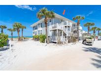 Coastal beach house with white railings and stairs plus tropical landscaping and a golf cart at 7548 Palm Island S Dr # 1724, Placida, FL 33946