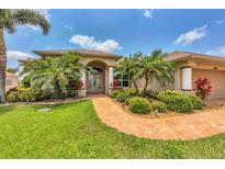 Charming single-Gathering home featuring lush landscaping, a terracotta walkway, and a well-manicured lawn at 8180 Burwell Cir, Port Charlotte, FL 33981