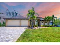 Beautiful home featuring a paver driveway leading to a spacious three-car garage at 8400 Antwerp Cir, Port Charlotte, FL 33981