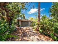 Charming home with a garage and driveway, surrounded by lush greenery and mature trees, offering a secluded and private setting at 875 Morrison Ave, Englewood, FL 34223
