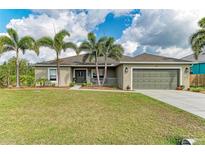 Charming single-story home with mature palm trees, lush green lawn, and a welcoming front porch at 9211 Koma St, Port Charlotte, FL 33981
