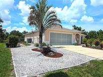 Charming single-story home featuring a well-manicured yard with a decorative rock garden and mature landscaping at 10064 Cocoa Beach St, Port Charlotte, FL 33981