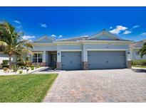Beautiful single-story home with a three-car garage, brick driveway, and lush landscaping with palm trees at 15176 Spanish Point Dr, Port Charlotte, FL 33981