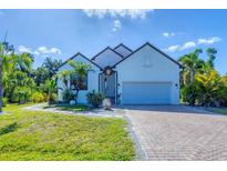 Charming single-Gathering home with a well-manicured lawn, brick driveway, and tropical landscaping at 161 Haddock Dr, Rotonda West, FL 33947