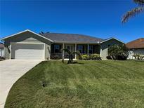 Charming single-story home with a well-manicured lawn, landscaped garden, and a two-car garage at 174 Broadmoor Ln, Rotonda West, FL 33947