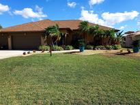 Charming home with tropical landscaping, well-maintained lawn, and a spacious driveway at 19 Medalist Way, Rotonda West, FL 33947