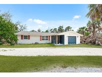 Charming single-story home with a garage and a screened-in porch, surrounded by lush greenery and a gravel driveway at 4065 N Beach Rd, Englewood, FL 34223