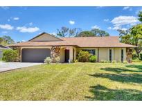 Charming single-story home featuring a well-manicured lawn, a stone-accented facade, and an attached two-car garage at 5879 Venisota Rd, Venice, FL 34293