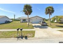 Charming single-story home with a well-maintained lawn and an attached two-car garage on a sunny day at 6255 Coniston St, Port Charlotte, FL 33981