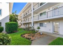 Condo exterior featuring well-maintained landscaping, a small bench, and black railings at 708 Tamiami S Trl # 216, Venice, FL 34285