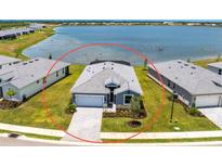 Beautiful single-Gathering home with grey paint and tile roof, lakeside views, and well-manicured lawn at 8244 Shore Lake Dr, Englewood, FL 34224