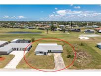 Aerial view of charming single-story home on a golf course with a long driveway and mature landscaping at 11 Oakland Hills Rd, Rotonda West, FL 33947
