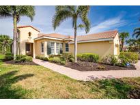 Inviting single-story home with lush landscaping, a brick walkway, and a beautiful terra cotta tile roof at 142 Savona Way, North Venice, FL 34275