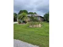 Charming single-story home featuring lush landscaping, mature trees, and a well-manicured lawn at 142 Yellow Pine Dr, Rotonda West, FL 33947
