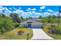 Charming single-story home features a well-manicured lawn, attached garage, and a cozy, inviting front porch at 149 Garland Way, Rotonda West, FL 33947