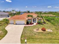 Beautiful waterfront home featuring mature landscaping, an arched entry, and a three-car garage at 15020 Acorn Cir, Port Charlotte, FL 33981