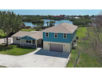Waterfront home with a two-car garage and well-maintained lawn at 1605 Manor Rd, Englewood, FL 34223