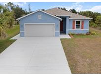 Charming single-story home with a two-car garage, light blue paint, and fresh landscaping at 1664 Karluk St, North Port, FL 34287