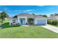Inviting single-story home with a well-manicured lawn, featuring a modern blue front door and coordinated garage door at 171 Mark Twain Ln, Rotonda West, FL 33947