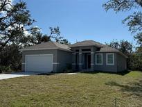 Single-Gathering home featuring a well-maintained lawn and a two-car garage at 18043 Hillsborough Blvd, Port Charlotte, FL 33954