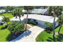 Beautiful home with tropical landscaping, a white tile roof and a paved driveway and sidewalks at 19 Oakwood Dr N # 19, Englewood, FL 34223