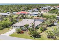 Charming home with lush landscaping, a canal view, and an attached two-car garage at 2441 Vance Ter, Port Charlotte, FL 33981
