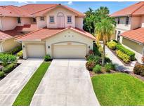 Beautiful two-story villa with a terra cotta roof, multiple car garage, and tropical landscaping at 4612 Club Dr # D102, Port Charlotte, FL 33953