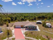 Charming home with a red driveway, white rock landscaping, and a large lawn backing up to water at 6417 Klaus Ct, Port Charlotte, FL 33981