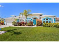 Charming single-story home with a well-manicured lawn, colorful landscaping, and a vibrant blue front door at 116 Tournament Rd, Rotonda West, FL 33947