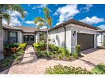 Charming single-story home featuring a landscaped front yard, brick pathway, and tropical palm trees against a blue sky at 13859 Vadini St, Venice, FL 34293