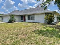 Charming single-story home with a red door, attached garage, and well-maintained lawn under a partly cloudy sky at 22589 Nyack Ave, Port Charlotte, FL 33952