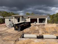 New construction home featuring a two-car garage, concrete walls, and grey roof under a dramatic, cloudy sky at 8270 Cook Ct, Port Charlotte, FL 33981