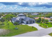 Wide aerial view of a single-Gathering home with dark roof, manicured lawn, and a three car garage at 9532 Miami Cir, Port Charlotte, FL 33981