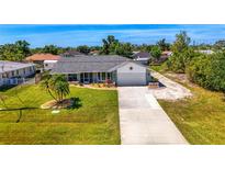 Charming one-story home featuring a long driveway, a well-manicured lawn and a tropical tree at 9869 Gulfstream Blvd, Englewood, FL 34224