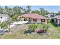 Charming single-story home with well-maintained landscaping, circular driveway, and a red tile roof at 13080 Proctor Ave, Port Charlotte, FL 33981