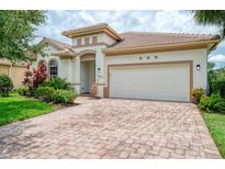 Charming single-story home featuring a brick driveway, two-car garage, and beautifully landscaped front yard at 13282 Scrub Jay Ct, Port Charlotte, FL 33953