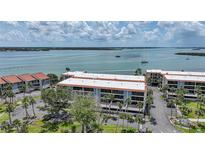 Aerial view of condos with mature landscaping, with a bay and boats, under a partly cloudy sky at 1501 Beach Rd # 310, Englewood, FL 34223