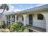 Condo's exterior features archways, a balcony, and lush tropical landscaping at 1730 Manasota Beach Rd # 204, Englewood, FL 34223