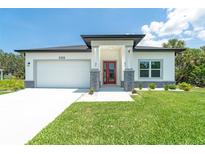 Charming single-story home with a red front door, lush green lawn, and attached two car garage at 398 Sunset N Rd, Rotonda West, FL 33947
